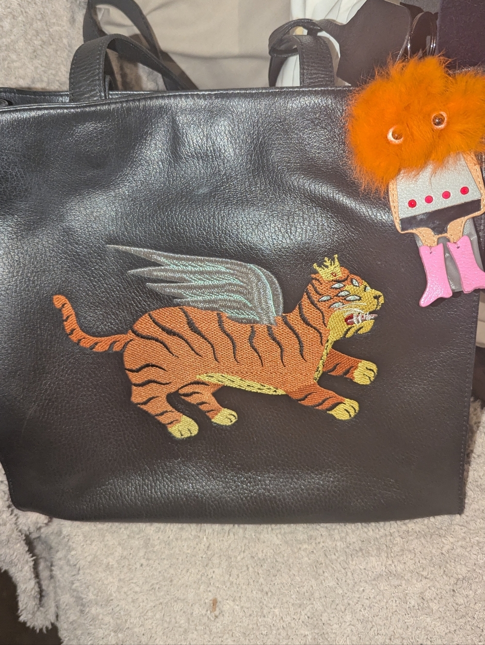 Min & Mon Black Leather Marko Tote with Winged Tiger Patch and Orange Pom Charm